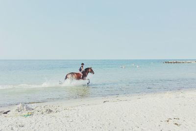 People on beach against clear sky