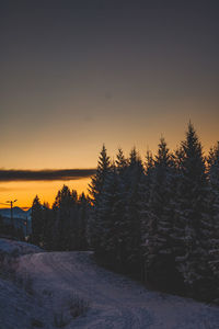 Snow covered land against sky during sunset