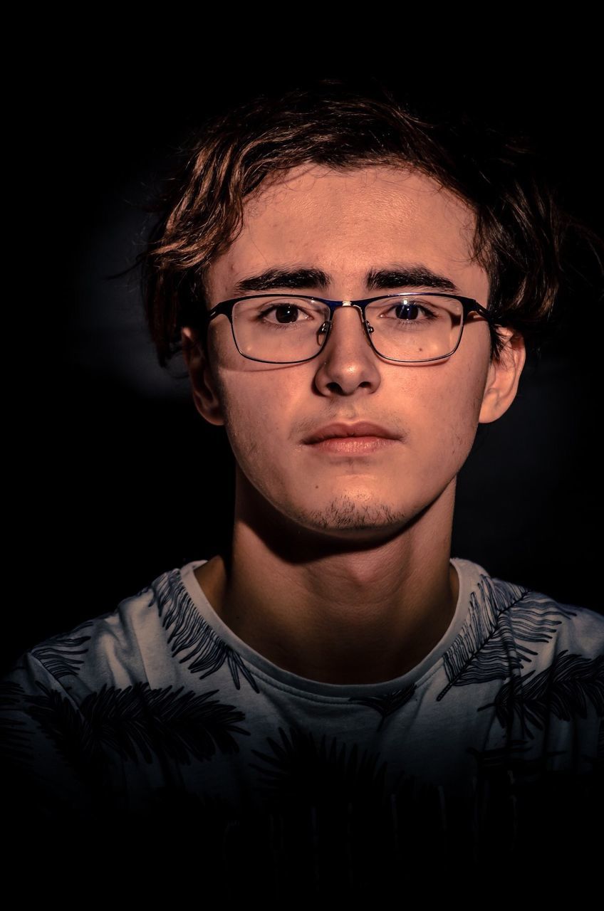 portrait, headshot, front view, one person, young adult, looking at camera, black background, young men, eyeglasses, indoors, glasses, studio shot, lifestyles, real people, close-up, beard, confidence, serious, human face, hairstyle, contemplation