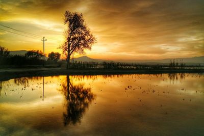 Scenic view of lake against dramatic sky during sunset