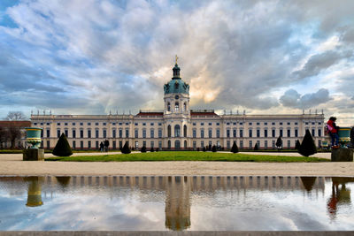 Reflection of building in lake against cloudy sky