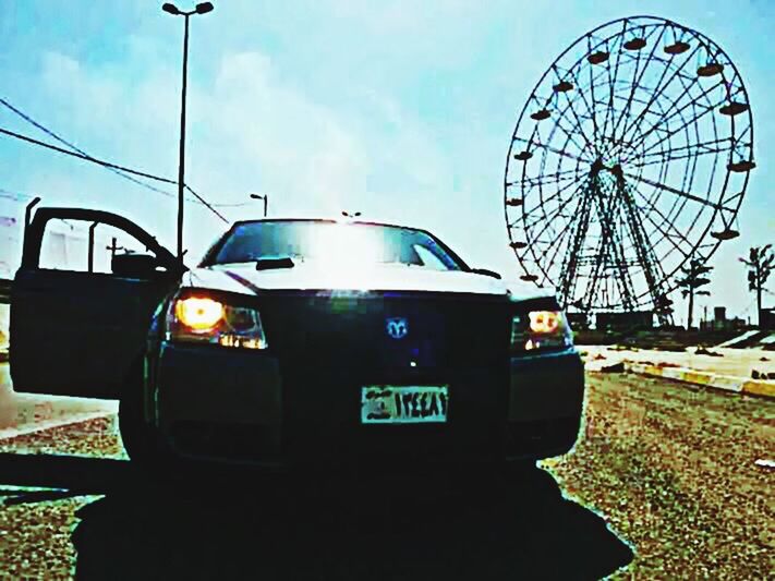 transportation, land vehicle, mode of transport, car, sky, travel, street, road, outdoors, low angle view, motorcycle, stationary, on the move, side-view mirror, no people, technology, ferris wheel, day, sunlight, sunset