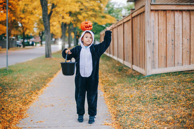 Cute boy with pumpkin standing outdoors