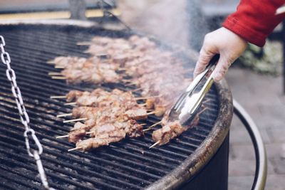 Cropped hand preparing food on barbecue grill