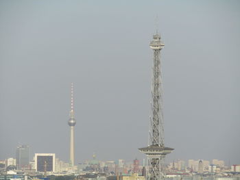 Communications tower in city against clear sky