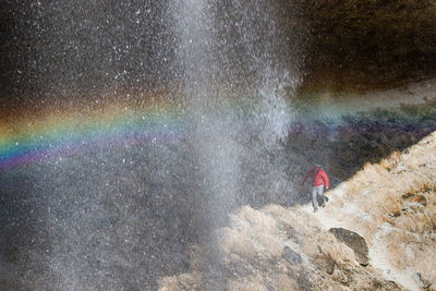 High angle view of woman walking on rock formation by waterfall