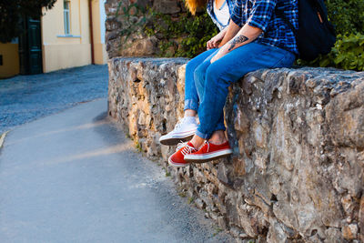 Low section of woman sitting on wall