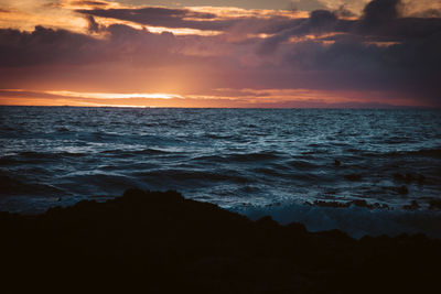 Scenic view of sea against cloudy sky during sunset