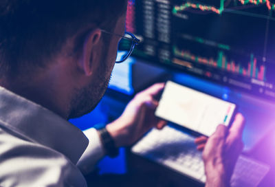 Caucasian professional trader in front of smartphone and desktop computer