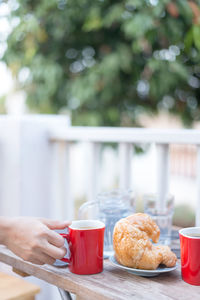 Cropped hand of woman holding coffee at table