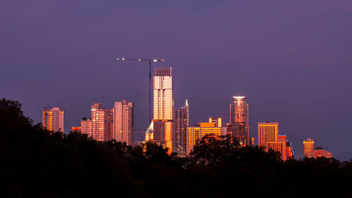 Illuminated buildings in city against sky at night