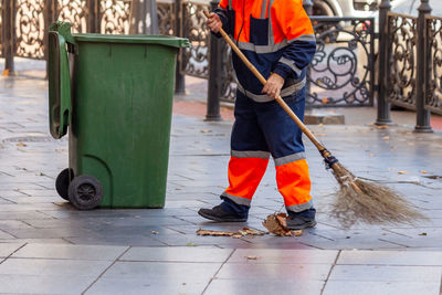 Low section of man working with garbage on footpath