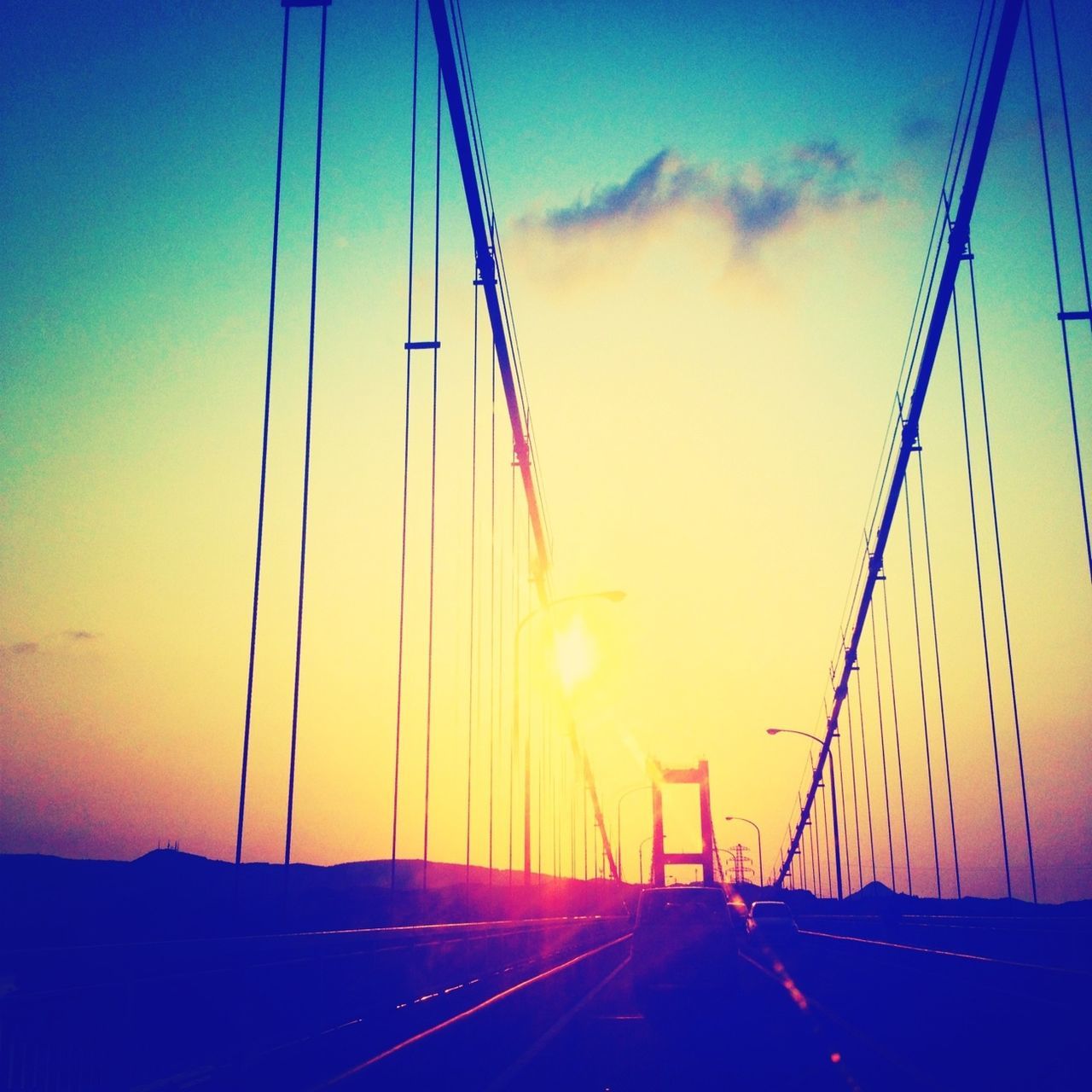 sunset, transportation, silhouette, sky, orange color, suspension bridge, connection, mode of transport, travel, car, dusk, beauty in nature, scenics, road, blue, outdoors, sun, nature, mast, travel destinations