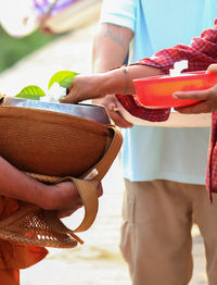 Midsection of man holding orange while standing at temple