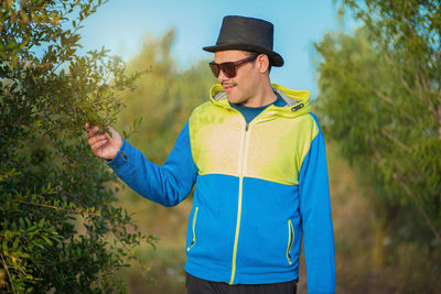 Young man wearing sunglasses standing against plants