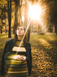 Young woman standing by tree