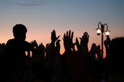 Silhouette people at music concert against sky during sunset