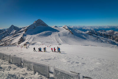 People on snowcapped mountains against sky