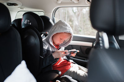 Boy sat in his car seat playing a nintendo video game console