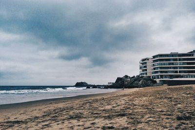 Scenic view of beach against cloudy sky