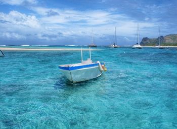 Boat sailing in sea against cloudy sky