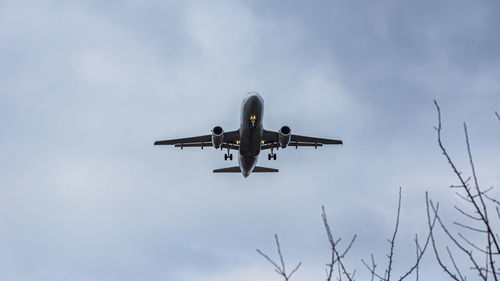 Low angle view of airplane flying in cloudy sky