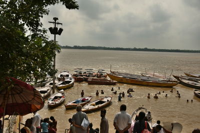 People on shore against sky