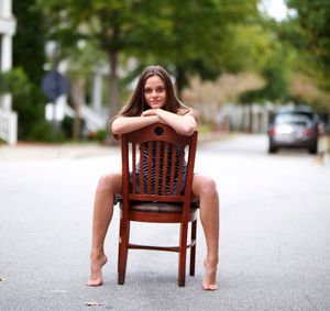 Portrait of young woman sitting on seat in city
