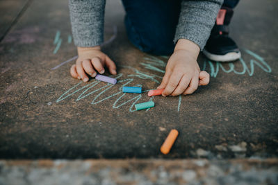 Child drawing with colored chalk on the floor