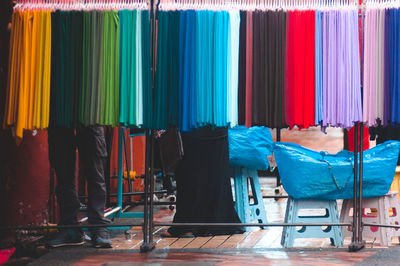Low section of people standing behind multi colored fabrics hanging on rack