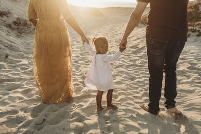 Behind view of young family walking at beach at sunset