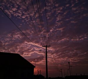 Low angle view of silhouette electricity pylon against romantic sky