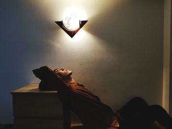 Low angle view of woman sitting on wall at home