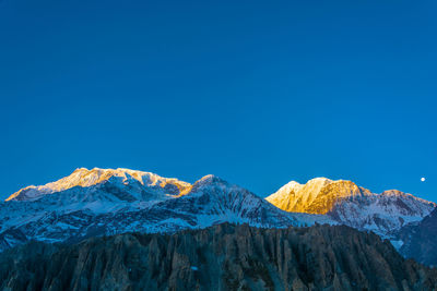 Scenic view of snowcapped mountains against clear blue sky