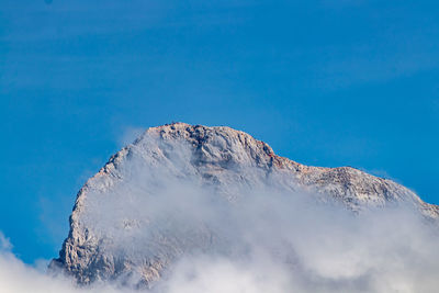 Low angle view of snowcapped mountain against blue sky