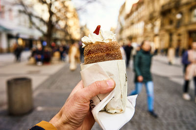 Cropped hand of man holding trdelnik, traditional czech sweet pastry 