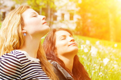 Close-up of sisters with closed eyes sitting on grass