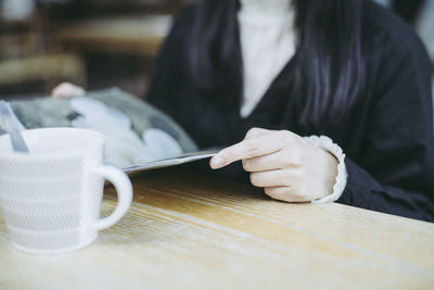 Midsection of woman holding menu on table at restaurant