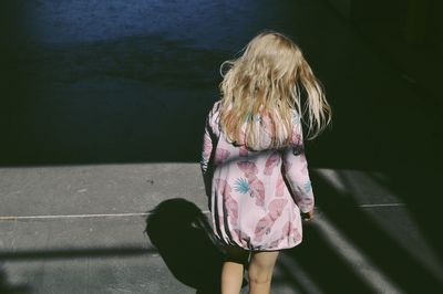 Rear view of girl with blond hair standing on road