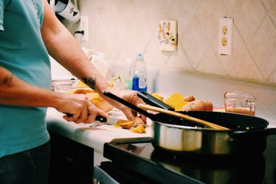 Midsection of woman cutting vegetable in kitchen