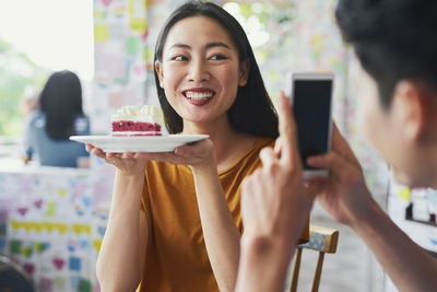 Portrait of smiling young woman holding mobile phone
