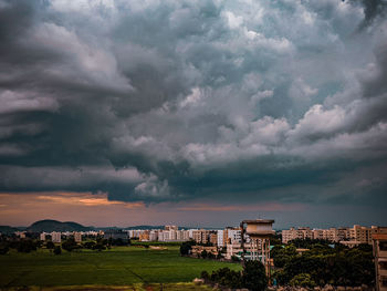 Buildings in city against dramatic sky