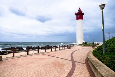 Lighthouse by sea against sky