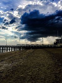 Pier on sea against cloudy sky