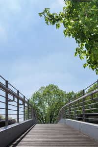 Footbridge amidst trees against sky