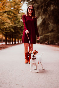 Portrait of young woman with dog standing outdoors