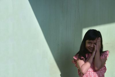 Portrait of a smiling young woman against wall