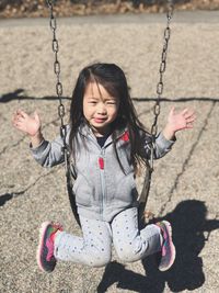 High angle portrait of girl sitting on swing at playground