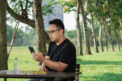 Man using phone while sitting at table outdoors