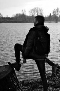 Rear view of man looking at lake against sky